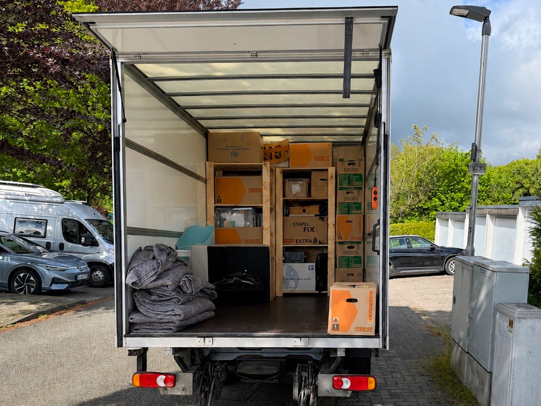 Beladener Umzugstransporter mit Kartons und Umzugsdecken vor einem Wohnhaus – Umzugsservice Lübeck