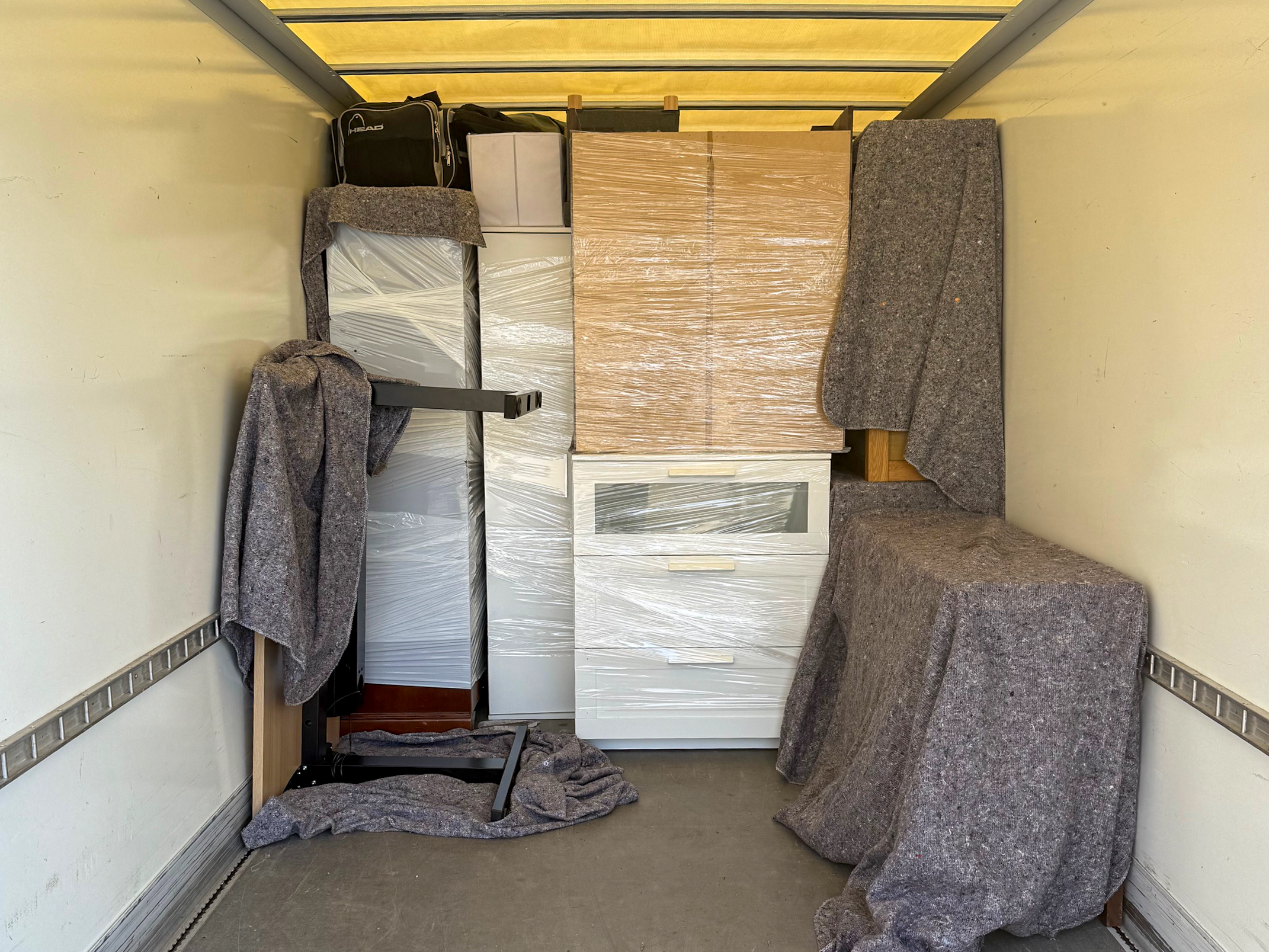 Sorgfältig mit Folie und Umzugsdecken verpackte Möbel im beladenen Umzugstransporter – Hansekraft Umzüge Lübeck